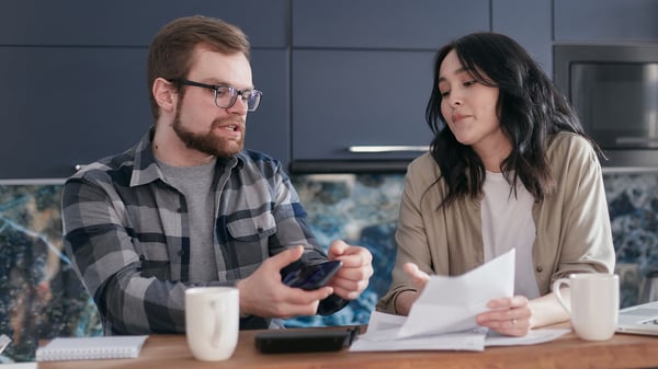 A couple reviews immigration paperwork at their kitchen table.