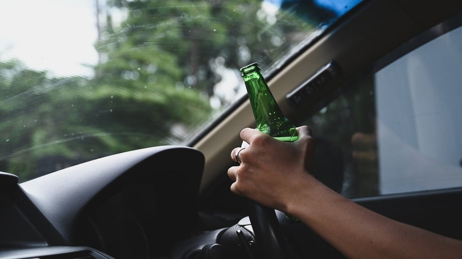 Driver holding an open beer bottle while gripping the steering wheel