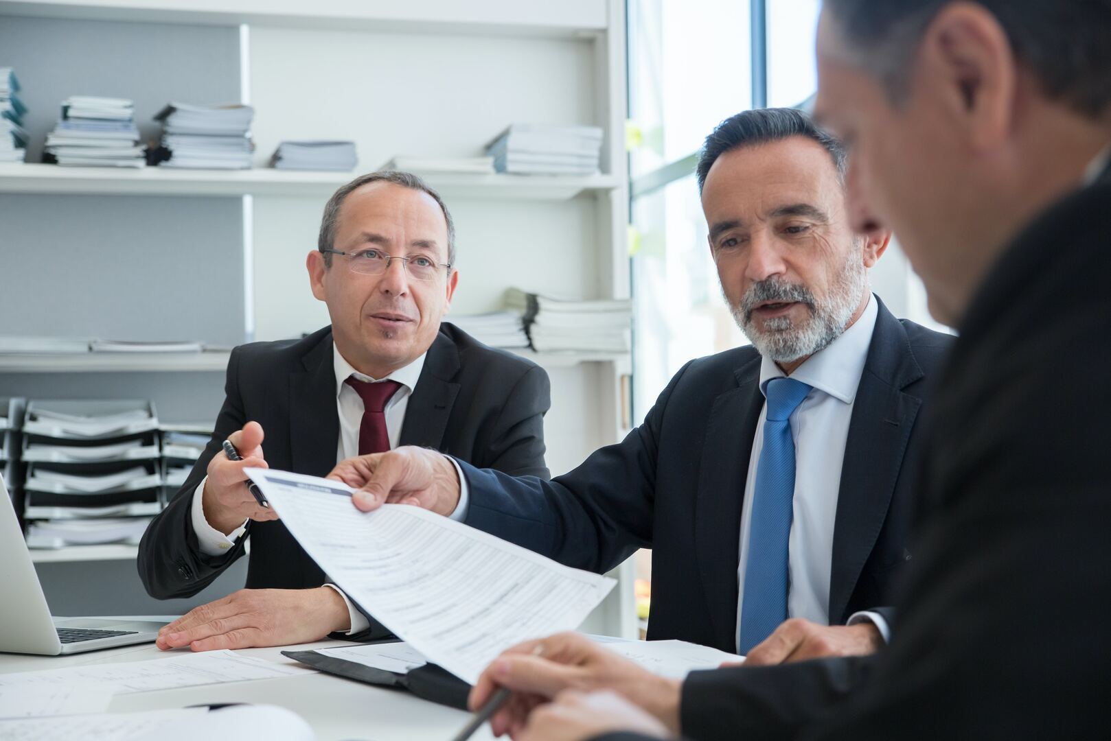 Tres profesionales revisan documentos en una oficina.