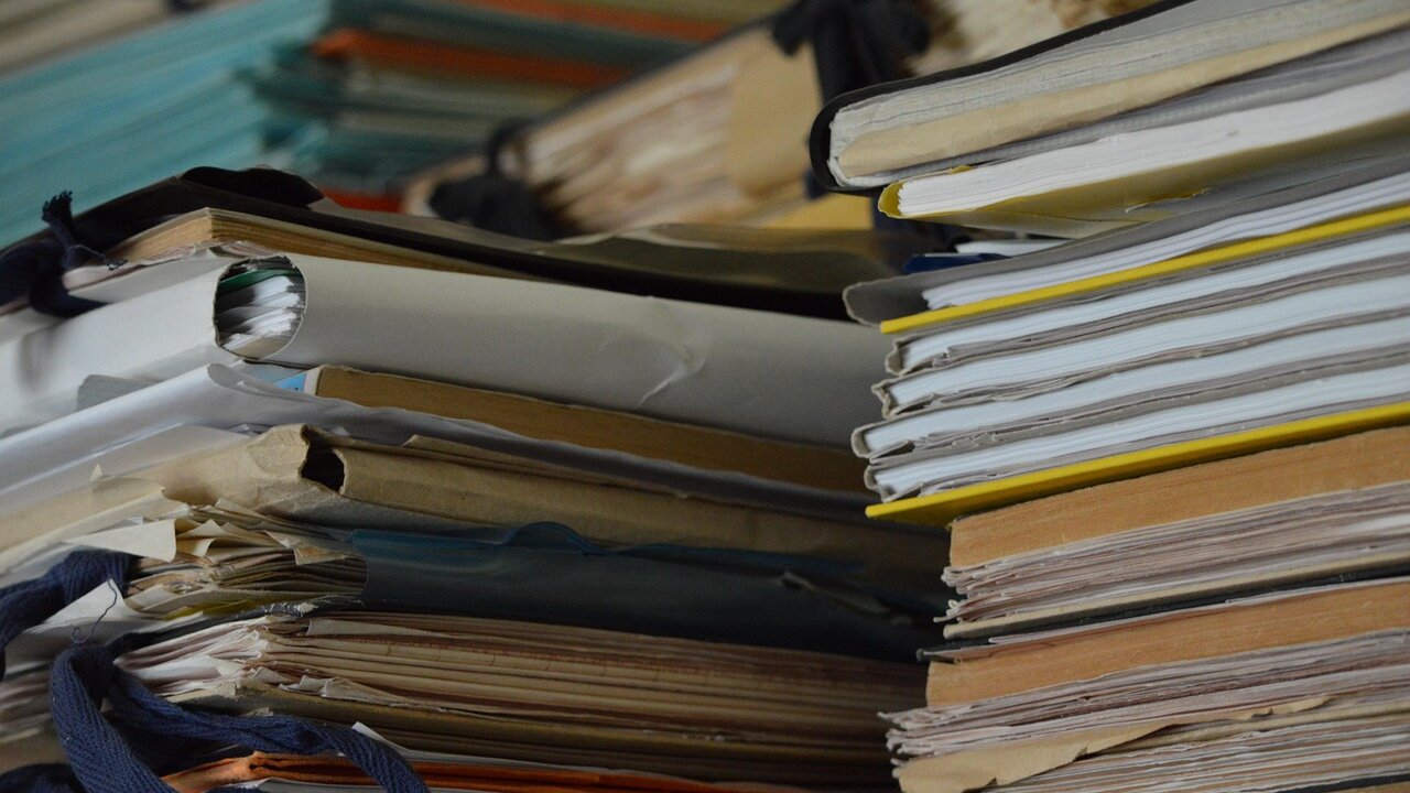 A tall, disorganized stack of worn file folders and papers, representing the volume of records in an immigration case file.